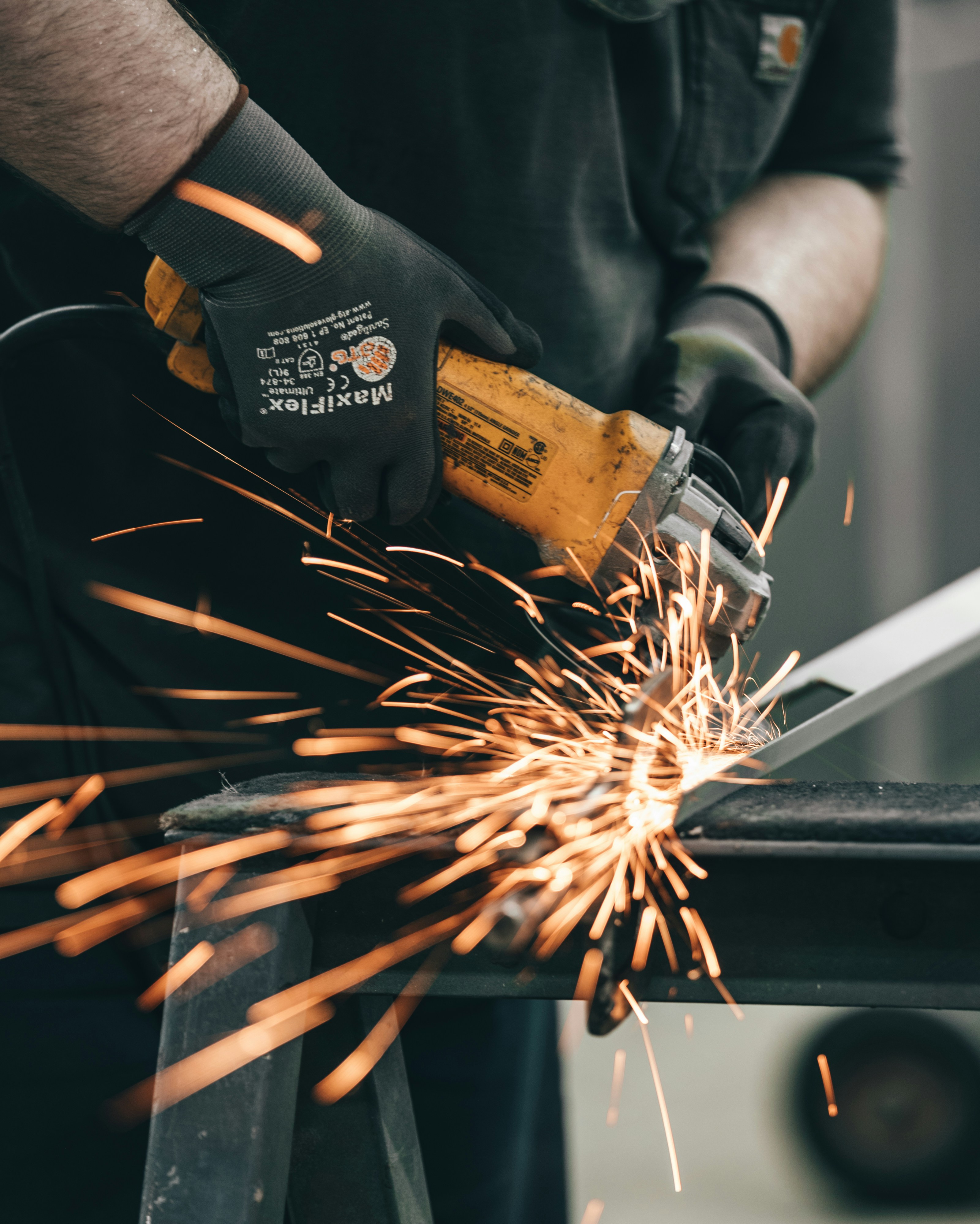 Handwerker trennt mit dem Winkelschleifer ein Metallprofil, Funken sprühen